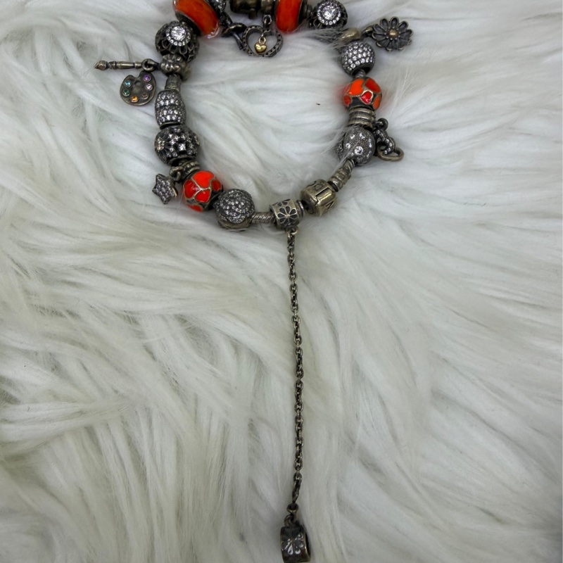 這是一條Pandora 品牌的串珠手鍊，上面配有各種銀製和鮮豔的橘色墜飾。-5