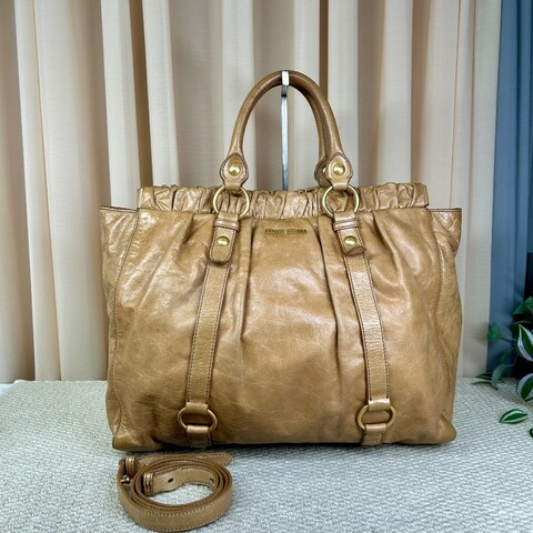 繆繆MiuMiu卡其色油蠟皮垃圾袋機車包 有肩帶 可單肩可斜挎可手提 油蠟皮質地 金屬圓環裝飾 上身就是鬆鬆垮垮垃圾袋感 容量大 日常通勤百搭實用