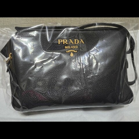 這是一件 Prada Vitello Phenix 黑色荔枝紋牛皮金色金屬標誌相機包。