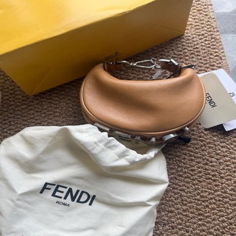 迷你Fendigraphy新月包,其現代造型飾以醒目細節。米色小牛皮材質,背攜時可看見底部的復古金色
