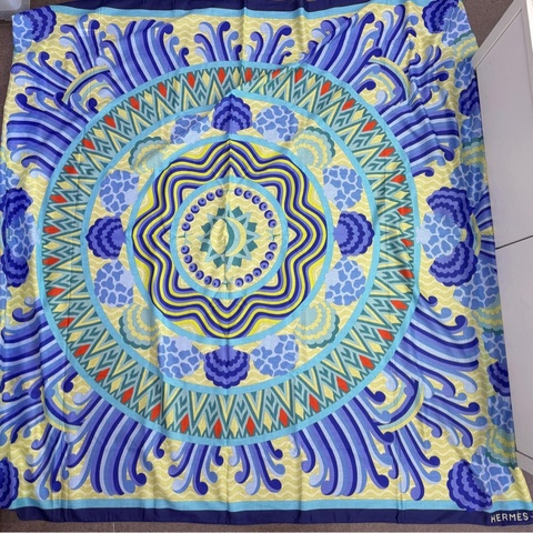 這是一條藍色和黃色調的愛馬仕（Hermès）絲巾，展現了複雜的幾何與圖騰設計