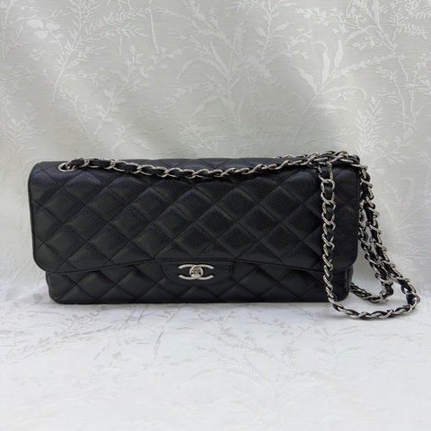 這是一只經典的黑色 CHANEL Classic Flap Jumbo 包款，採用耐用的魚子醬牛皮製成，並搭配銀色金屬鏈帶。